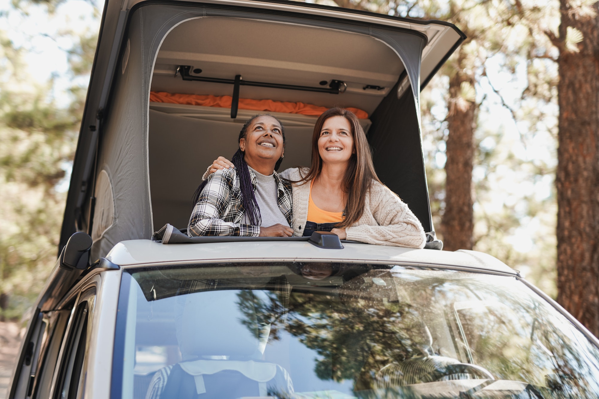 https://www.muchoneumatico.com/blog/wp-content/uploads/2022/10/multiracial-women-enjoy-road-trip-vacation-with-mini-van-camper-and-looking-out-on-roof-top.jpg